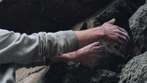 A rock climber's hands gripping onto rock cliff.