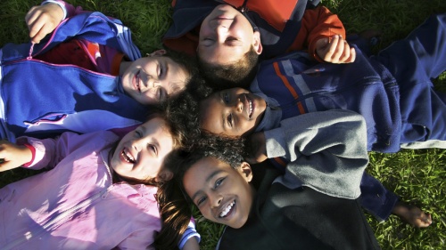 Young kids laying on the ground and looking up.