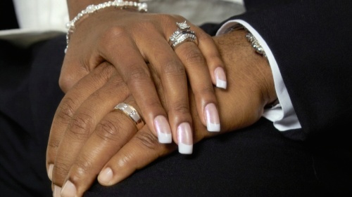 A couple holding hands showing their wedding rings.