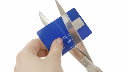 A person cutting a credit card with a pair of scissors.