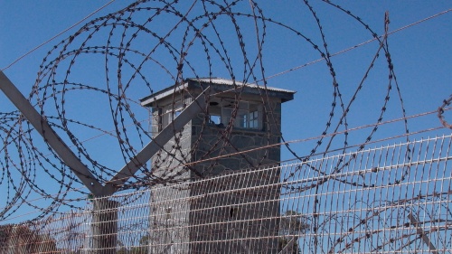 Barbed wire fence and tower in a prison yard.