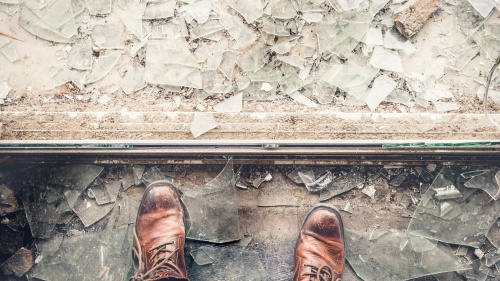 A person looking down at broken window glass.