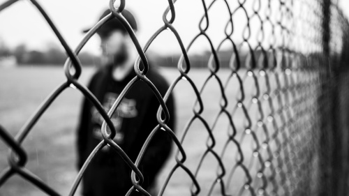A man standing behind a fence.