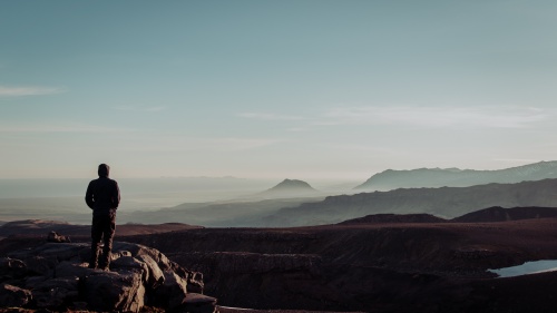 A young man standing on top of a cliff.