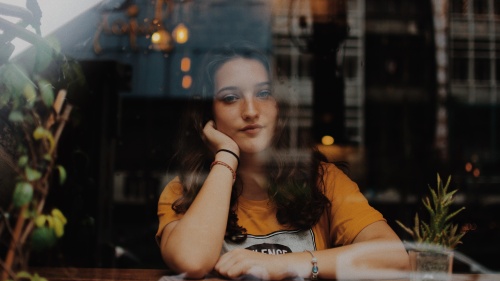 A young woman sitting with her arms on a counter looking through a window.