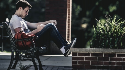 A man sitting on a park bench reading.