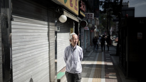 An older man walking down an alley street.