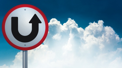 A u-turn type sign with the sky and clouds in the background.