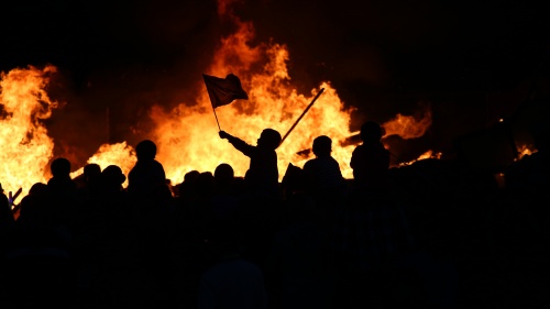 People at a riot burning items.