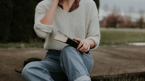 A woman sitting on the ground holding a Bible.