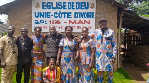 a group of people standing outside a building under a banner