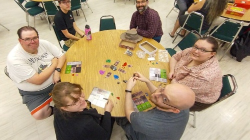 six people gathered around a table playing games