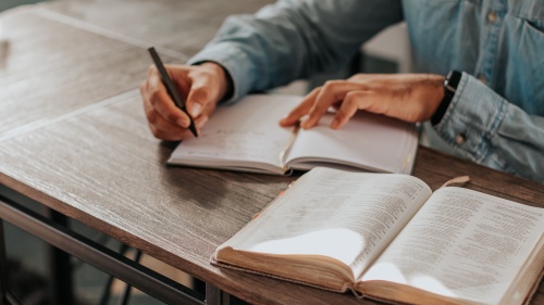 A person taking notes with a Bible open