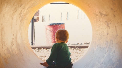 A little boy in a large concrete drain tube playing.
