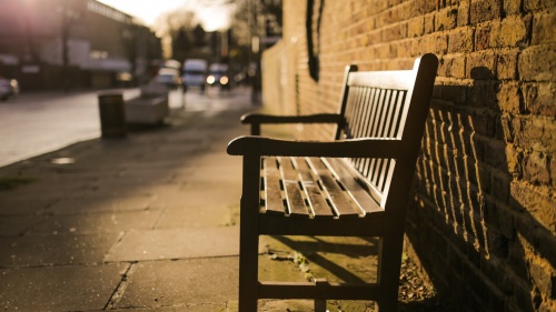 A empty bench on a sidewalk.