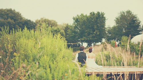 Married couple - man and woman - sitting on a dock.