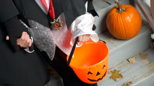 A little boy trick or treating with his mother.