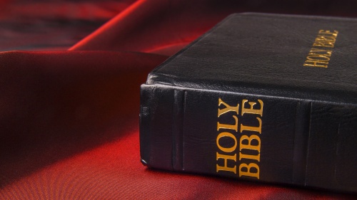 A Bible sitting on a red piece of cloth.