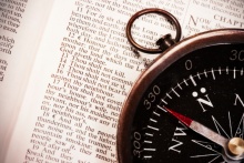 Compass laying on top of a Bible opened to Exodus 20 - where the 10 Commandments are listed.