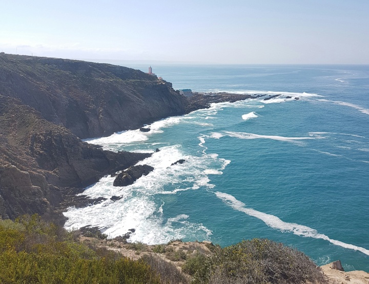 ocean water reaching a hilly coastline