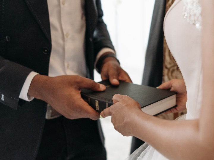 a bride and a groom holding a Bible together