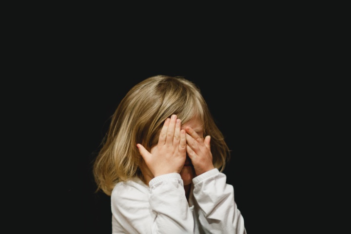 a child covering her face with her hands