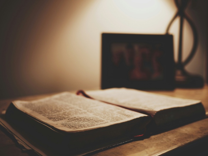 an open bible on a table in lamplight