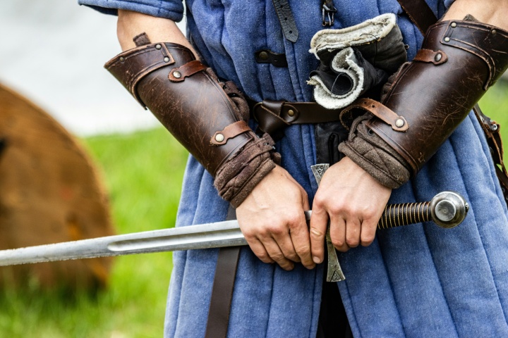 a person dressed in Medieval clothing and protective gear, holding a sword