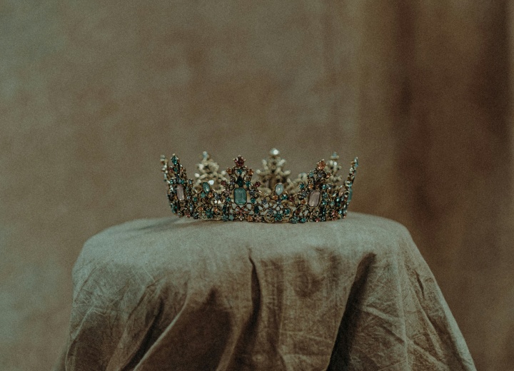 a crown displayed on a cloth-covered pedestal in a dimly-lit room