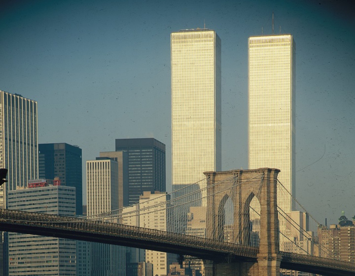 a historic image of the twin towers of the world trade center standing behind a bridge