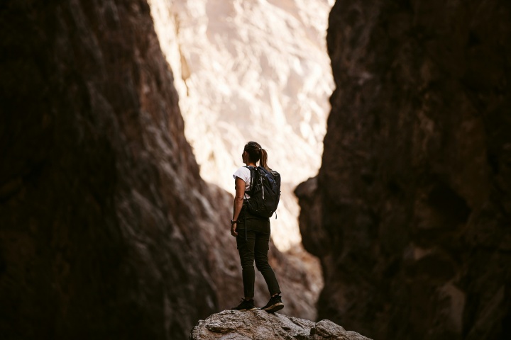 a woman standing on a rock surrounded on either side by a rockface