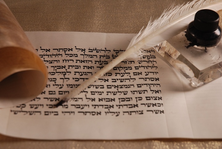 a scroll with Hebrew writing, a feather pen, and an inkwell