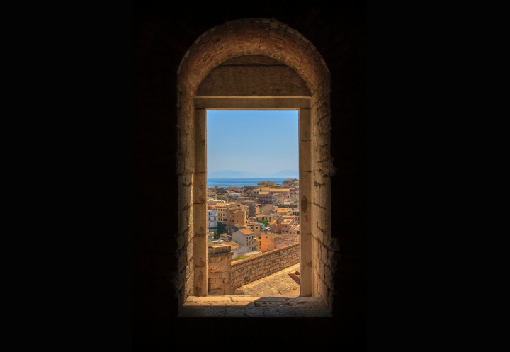 a door framed with a brick archway that looks out over a historic city