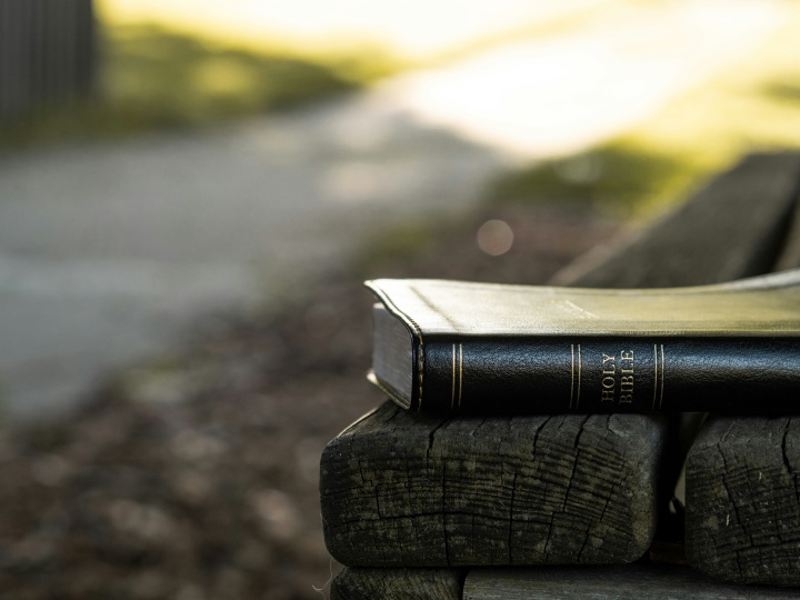 a Bible on a wooden bench outdoors