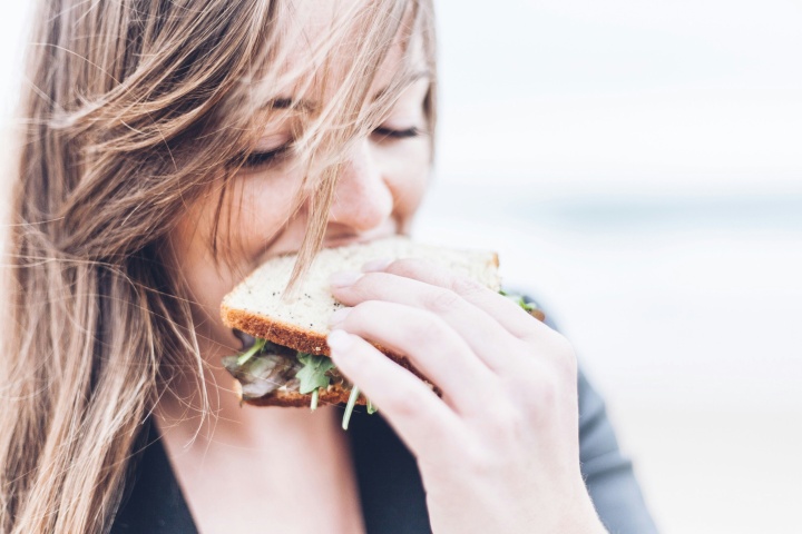 A young woman eating a healthy looking sandwich,