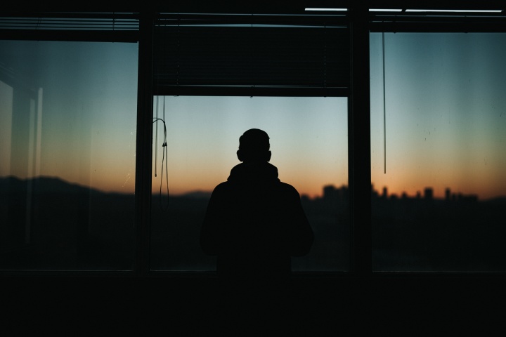 A silhouette of man standing by a window.