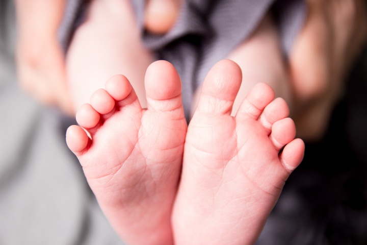A person holding the tiny feet of a baby.