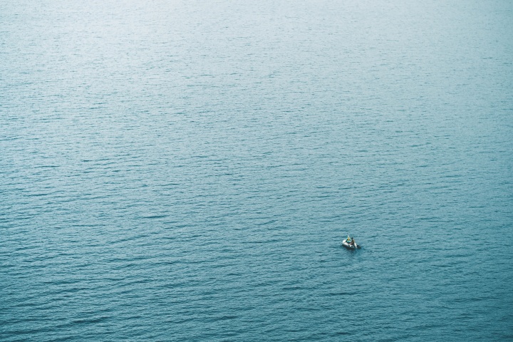 A tiny boat in a big sea of water.