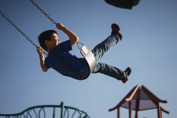 A boy swinging on a playground swing.