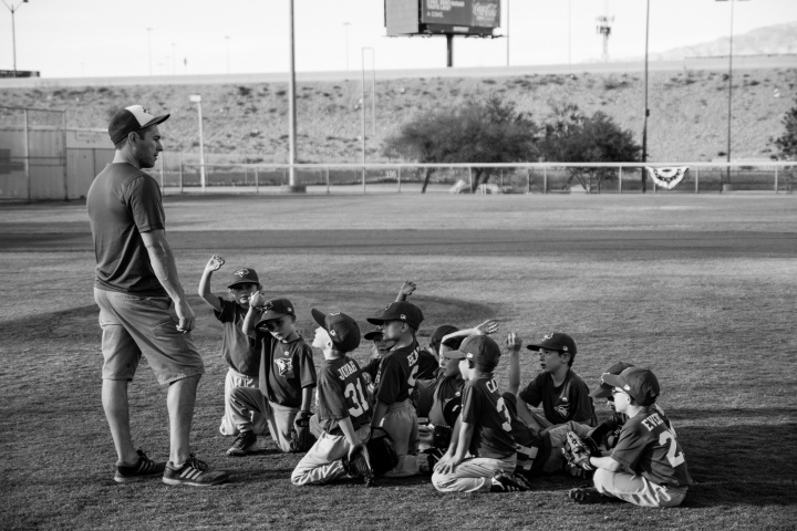 A little league baseball team look up at their coach.
