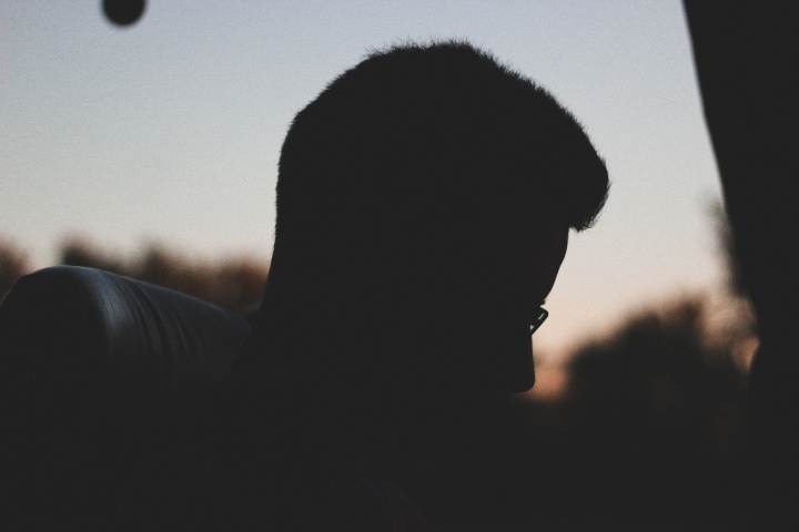 A silhouette of young man sitting in a bus.