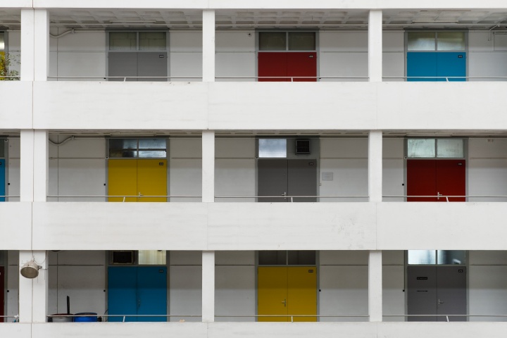 Outside of building with several floors featuring different colored doors.