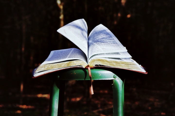 An open Bible on a metal stool.