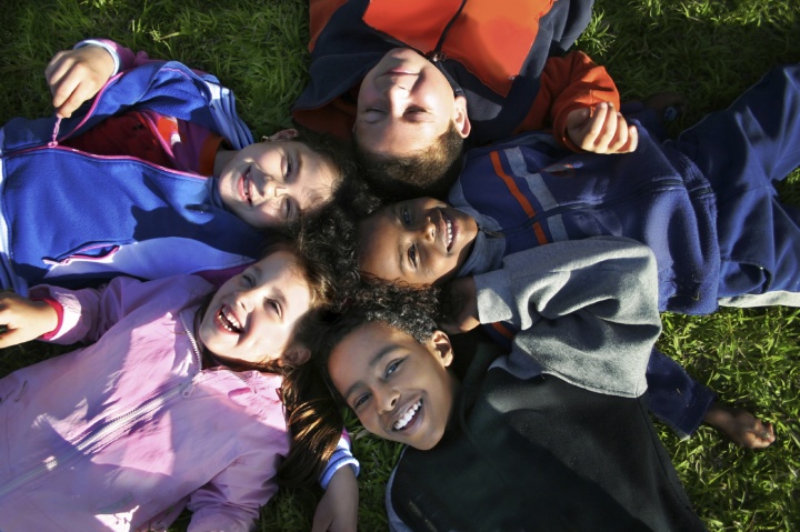 Young kids laying on the ground and looking up.