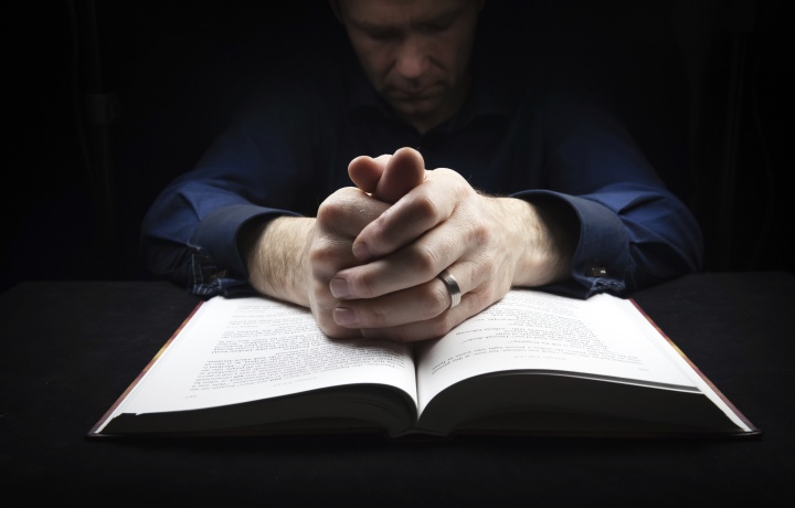 A man praying over his Bible.