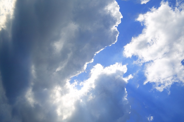 A blue sky with clouds and sun rays.