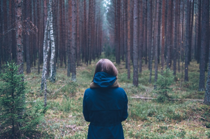 A young woman looking into a forest.