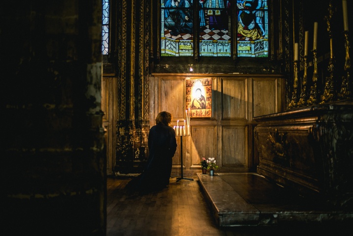 A woman praying to a painting hanging in a church.