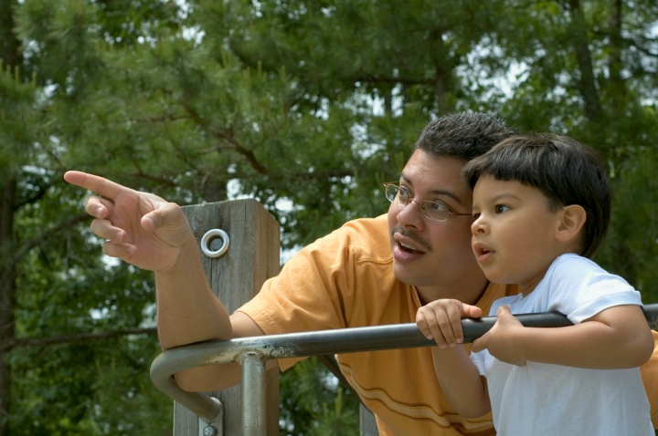 A dad and son playing at a park.
