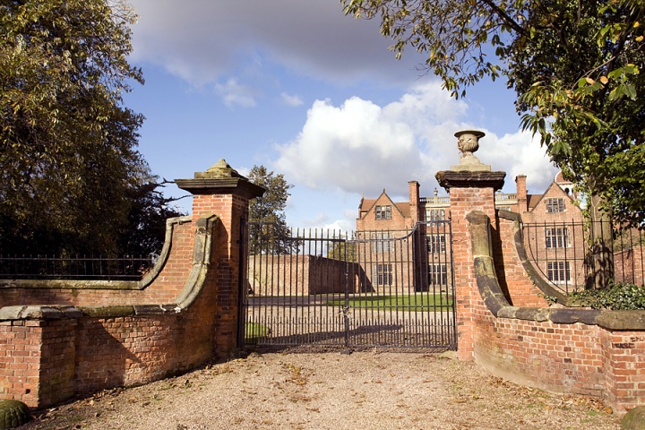 A big gate surrounding a large brick house.